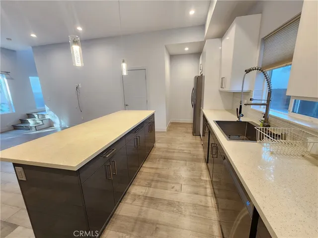 a kitchen with kitchen island granite countertop a sink and a stove top oven