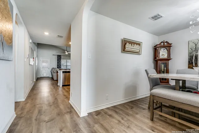 a view of a hallway with wooden floor and a bathroom