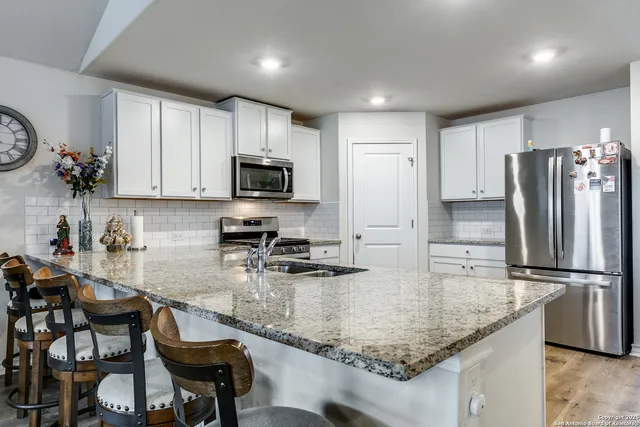 a kitchen with granite countertop a table chairs microwave and refrigerator