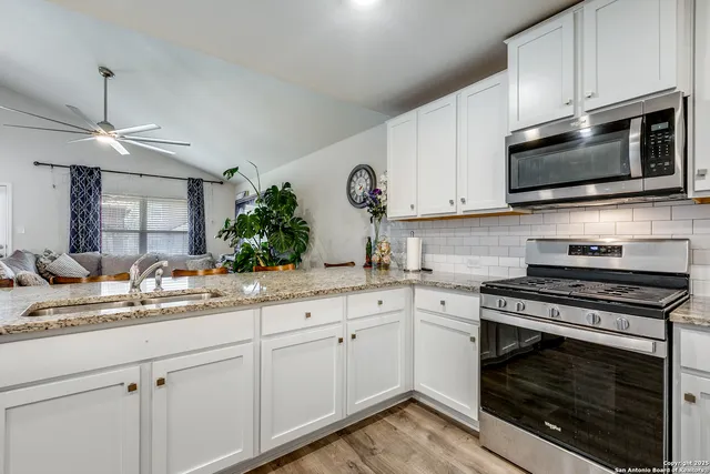 a kitchen with cabinets stainless steel appliances a sink and a stove