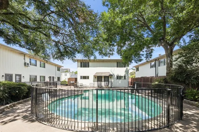 a view of a white house with large trees and plants