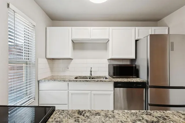 a kitchen with granite countertop a refrigerator and a stove top oven