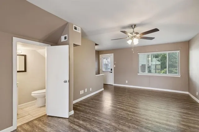 a view of an empty room with a window and wooden floor