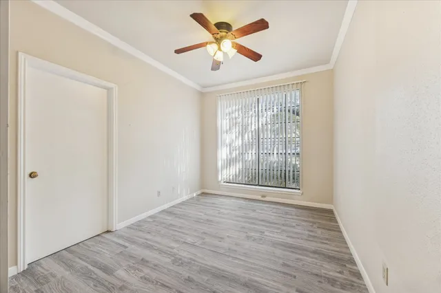 a view of an empty room with window and a fan