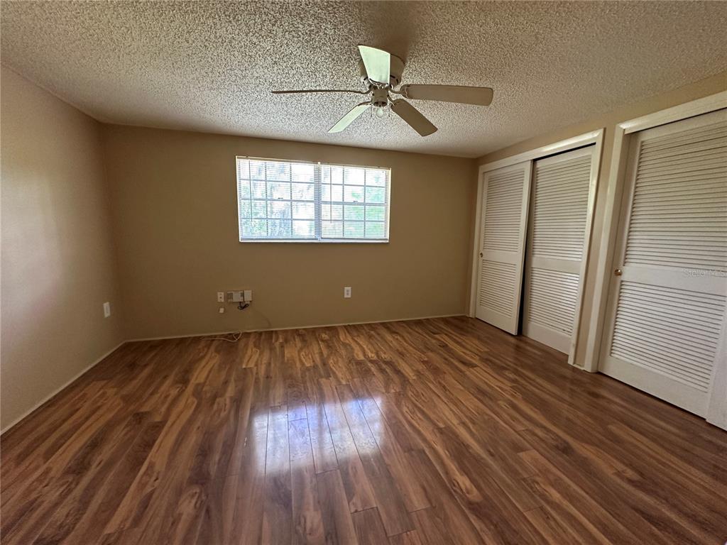 8809 Avondale Lane Hudson, FL 34667 - Photo 17 of 46 an empty room with wooden floor fan and windows