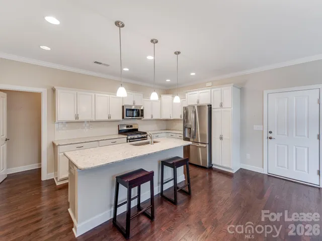 a large kitchen with stainless steel appliances a large counter top and wooden floors
