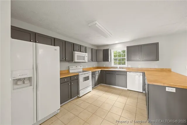 a large kitchen with a refrigerator a sink dishwasher a stove with cabinets and wooden floor