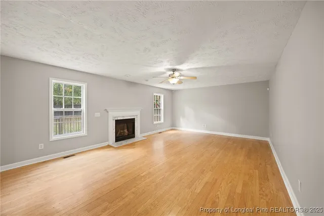 an empty room with chandelier fan and windows