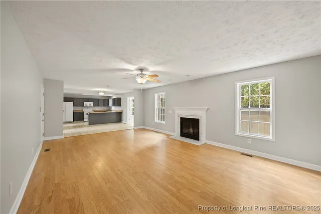 an empty room with fireplace chandelier fan and windows