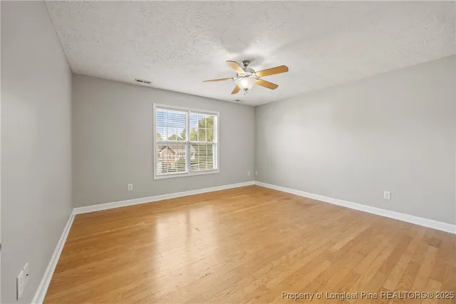 an empty room with windows and ceiling fan
