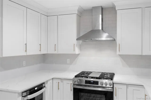 a kitchen with stainless steel appliances a stove and white cabinets