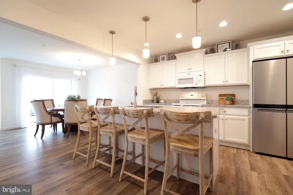 a kitchen with granite countertop white cabinets stainless steel appliances and wooden floor