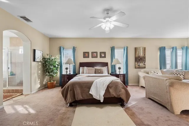 a spacious bedroom with a large bed and a chandelier