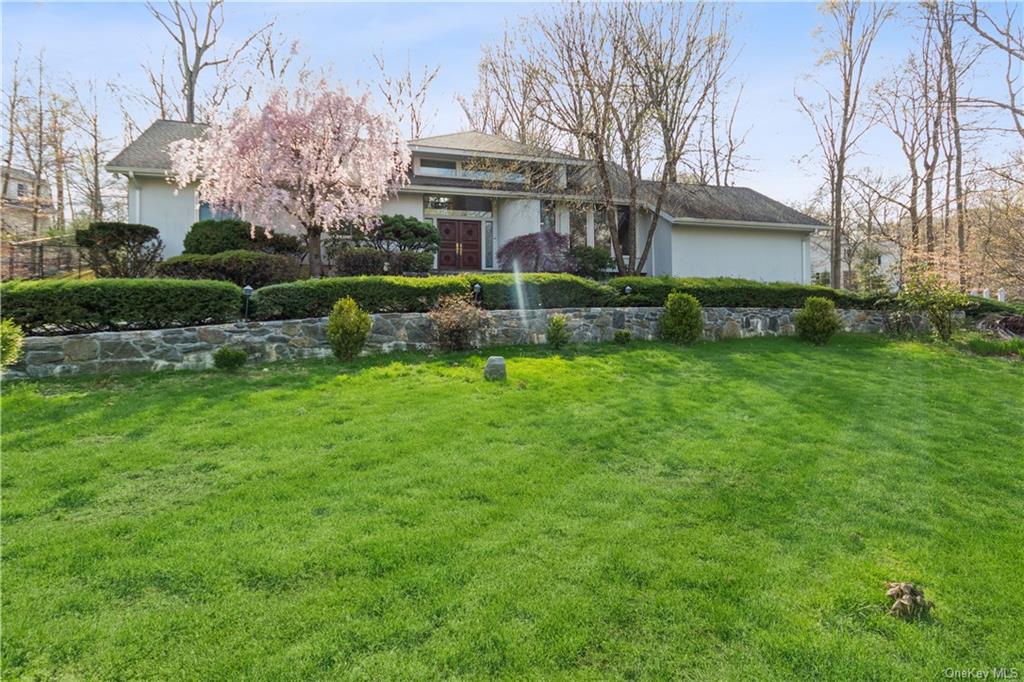 a view of a house with a big yard plants and large trees