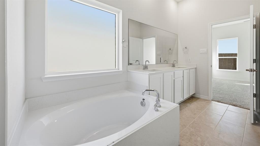 4163 Waldron Trail Forney, TX 75126 - Photo 14 of 30 Soaking tub with chrome fixtures, dual vanity with white cabinetry, large mirror, and tile flooring