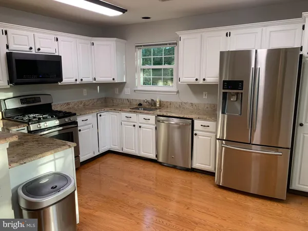 a kitchen with stainless steel appliances a stove a sink a microwave a refrigerator and cabinets