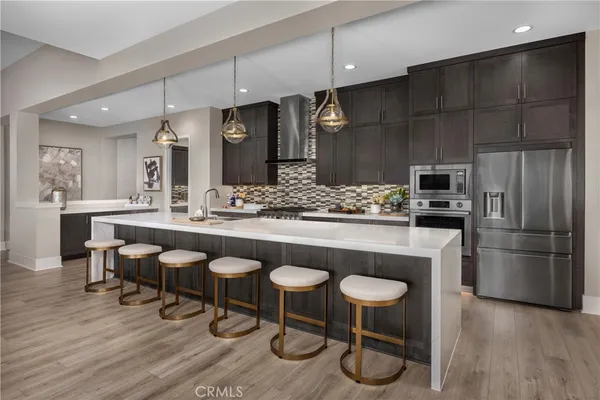 a kitchen with stainless steel appliances granite countertop a table chairs stove and refrigerator