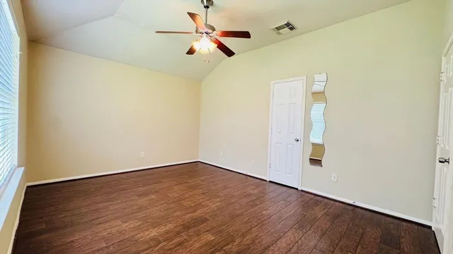 an empty room with wooden floor fan and white walls