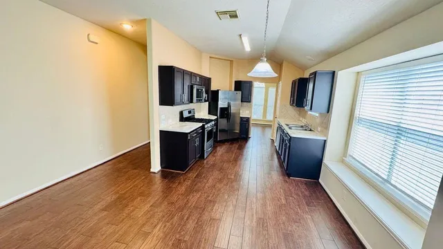 a room with stainless steel appliances a kitchen island hardwood floor sink stove and wooden floor