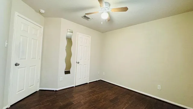 an empty room with wooden floor and fan
