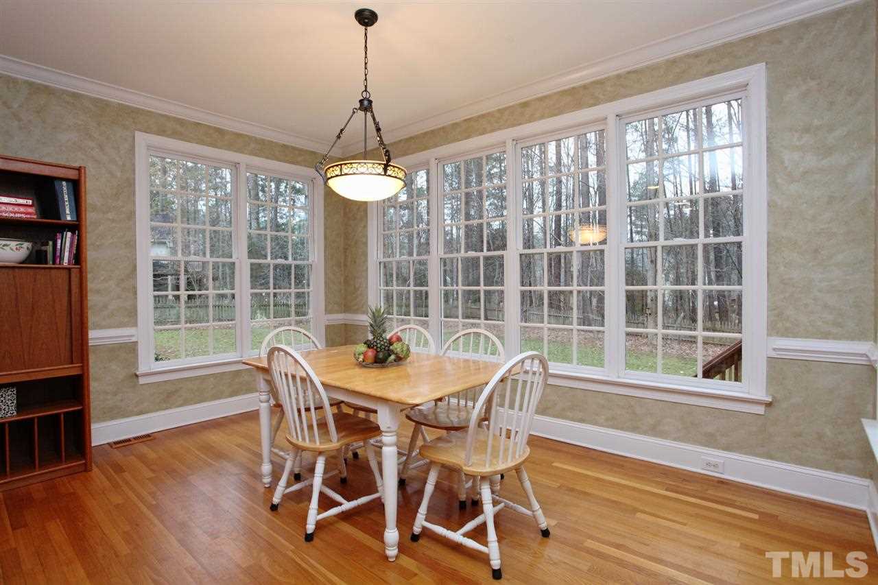 1405 Silverling Way Raleigh, NC 27613 - Photo 12 of 25 a dining room with wooden floor a chandelier a glass table and chairs
