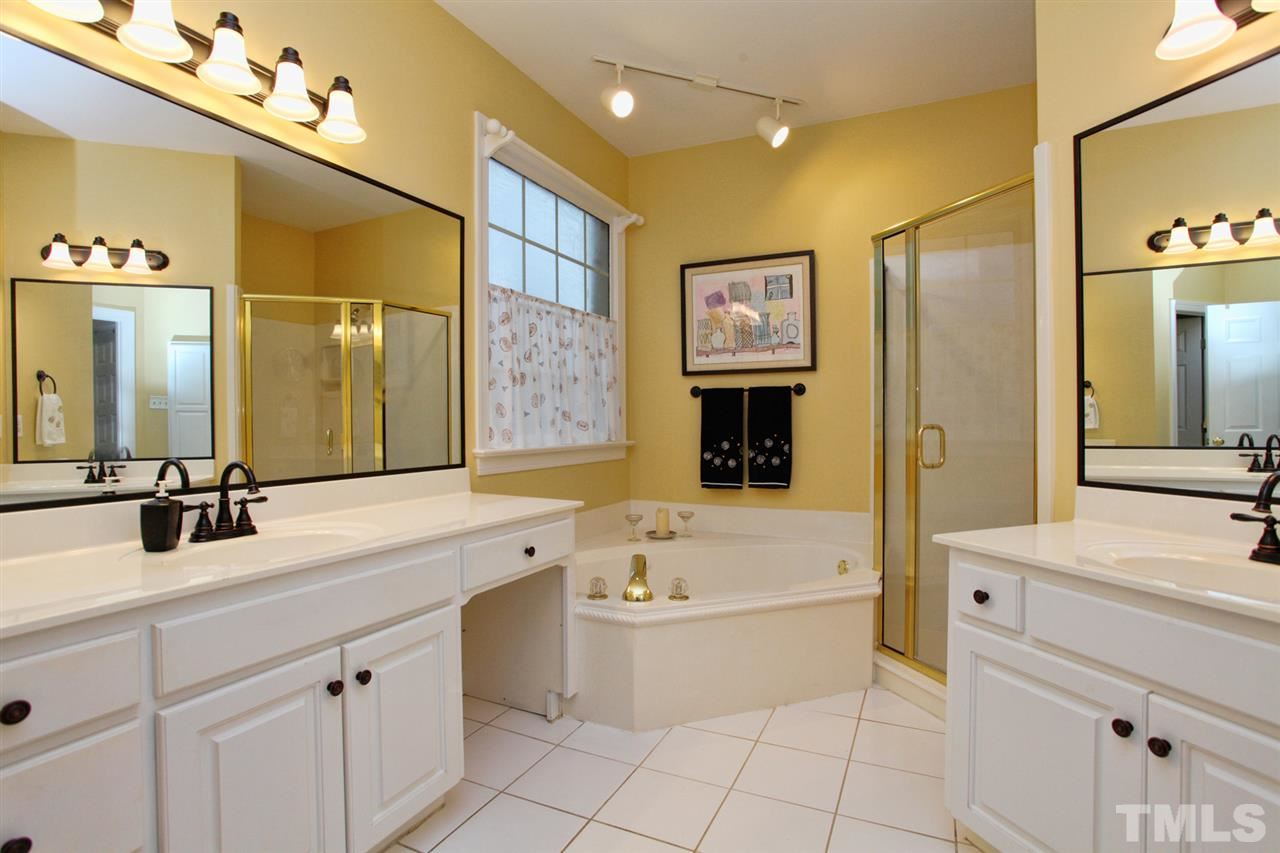 1405 Silverling Way Raleigh, NC 27613 - Photo 17 of 25 a bathroom with a tub a sink a mirror and a shower