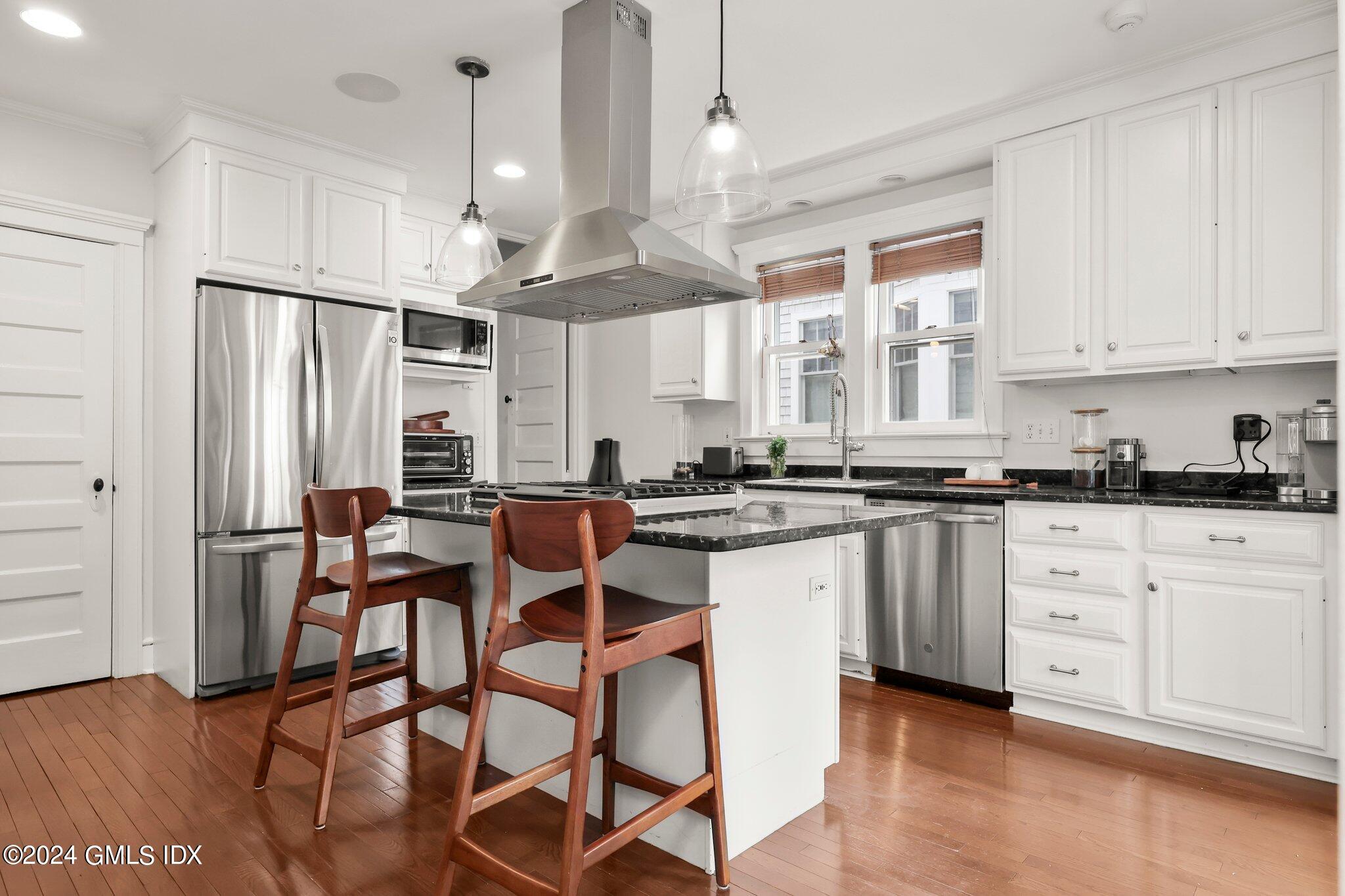 53 Ridge Street Greenwich, CT 06830 - Photo 13 of 26 a kitchen with stainless steel appliances kitchen island granite countertop a stove a refrigerator and white cabinets with wooden floor