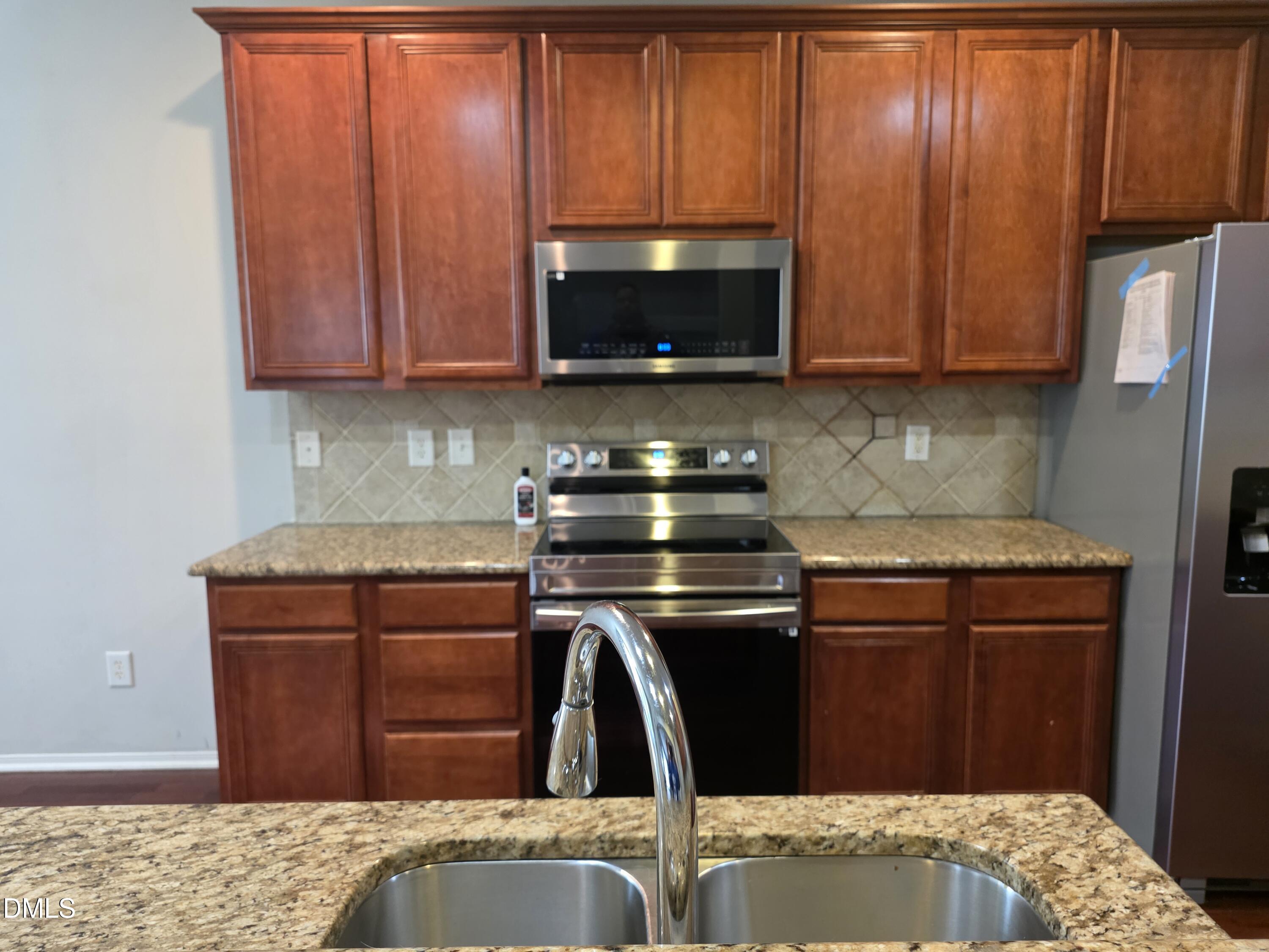 8208 Stone Cellar Drive Raleigh, NC 27613 - Photo 3 of 25 a kitchen with stainless steel appliances granite countertop wooden cabinets and a stove top oven