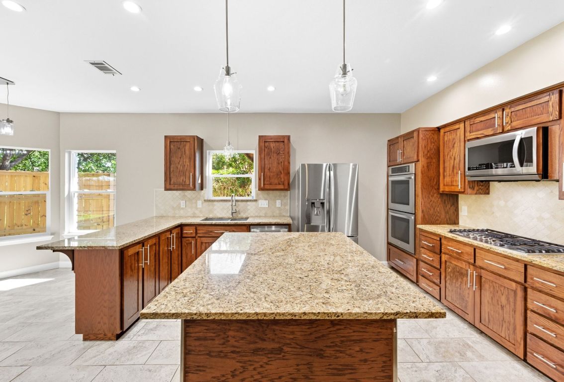 1904 Cedar Ridge Drive Austin, TX 78741 - Photo 12 of 40 a large kitchen with kitchen island granite countertop a large counter top stainless steel appliances and cabinets