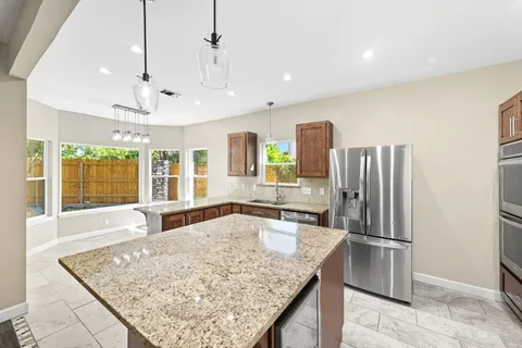 a large kitchen with kitchen island a large counter top space appliances and cabinets