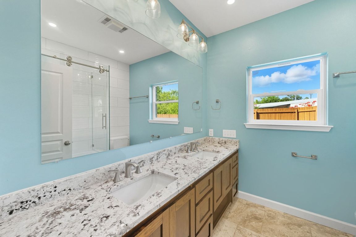 1904 Cedar Ridge Drive Austin, TX 78741 - Photo 22 of 40 a bathroom with a granite countertop sink a mirror and a