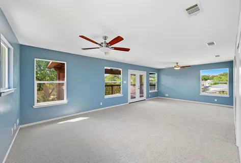 an empty room with windows and fan