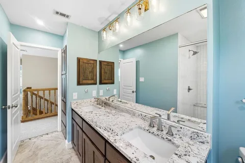 a bathroom with a granite countertop double vanity sink and mirror