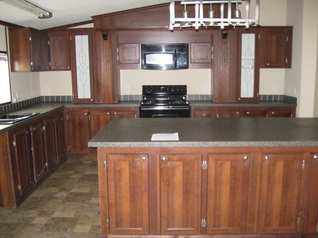 1064 Parrish Road Goodview, VA 24095 - Photo 17 of 21 a kitchen with granite countertop a refrigerator a stove and wooden cabinets