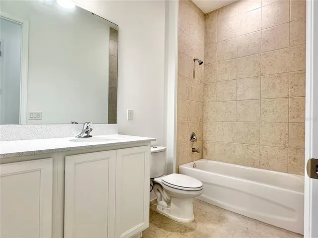 a bathroom with a granite countertop sink a toilet and bathtub