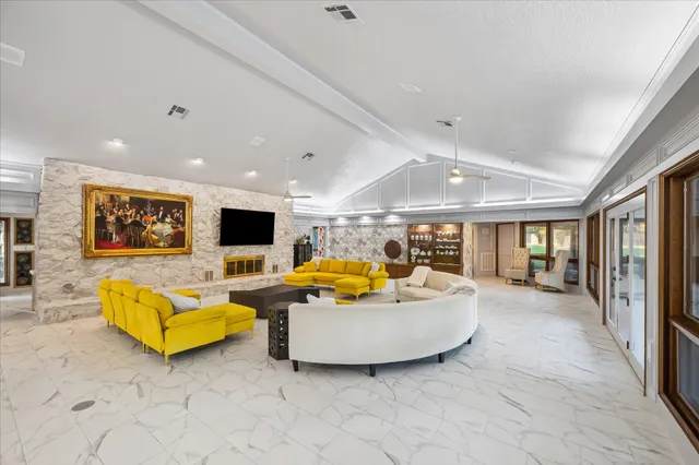 a living room with furniture fireplace and large windows