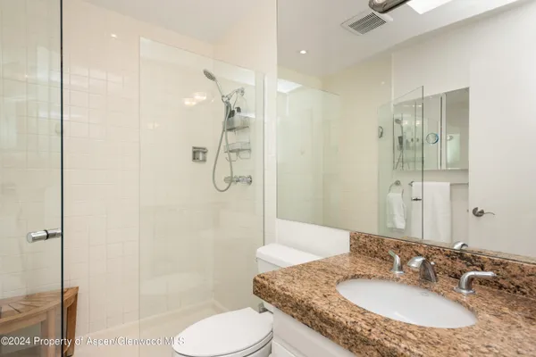 a bathroom with a granite countertop sink toilet and shower