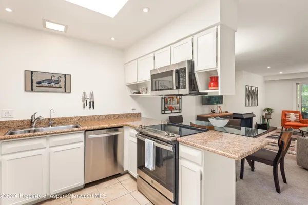 a kitchen with stainless steel appliances granite countertop a stove a sink and a microwave