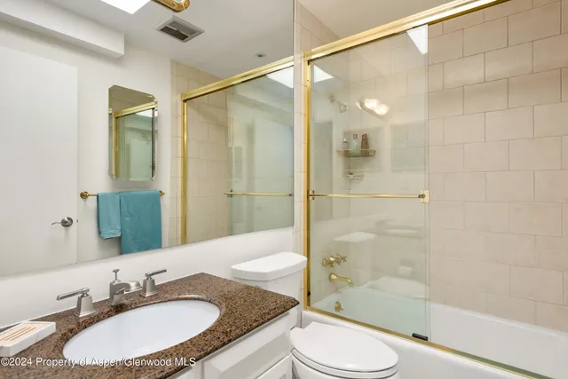 a bathroom with a granite countertop sink toilet and shower