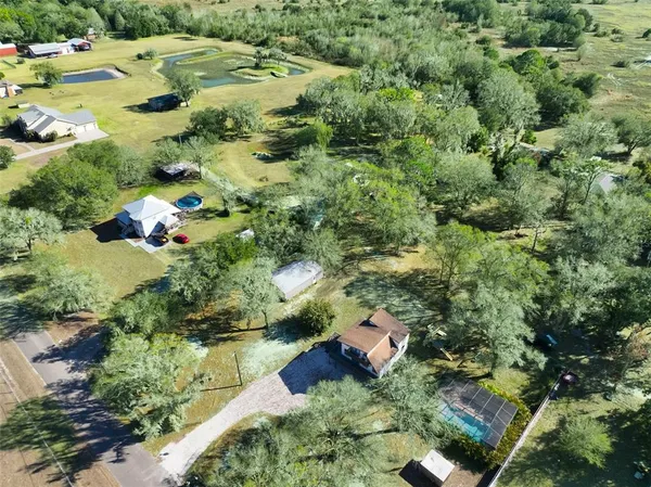 an aerial view of residential house with outdoor space and trees all around