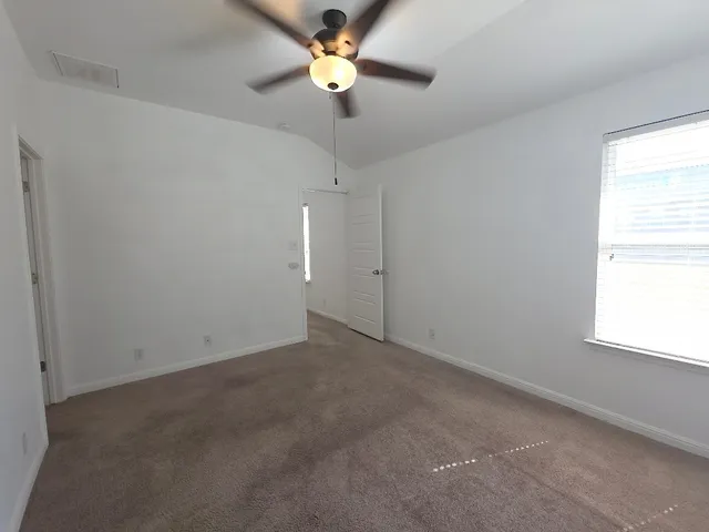 an empty room with a window and a fan