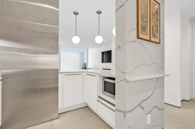 a white kitchen with a sink and dishwasher a refrigerator with white cabinets