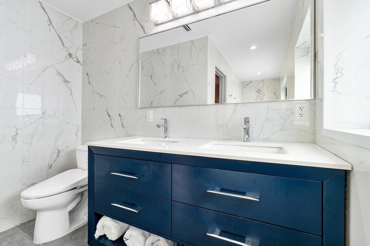 1280 Singer Drive Singer Island, FL 33404 - Photo 19 of 39 a bathroom with a double vanity sink toilet and a mirror