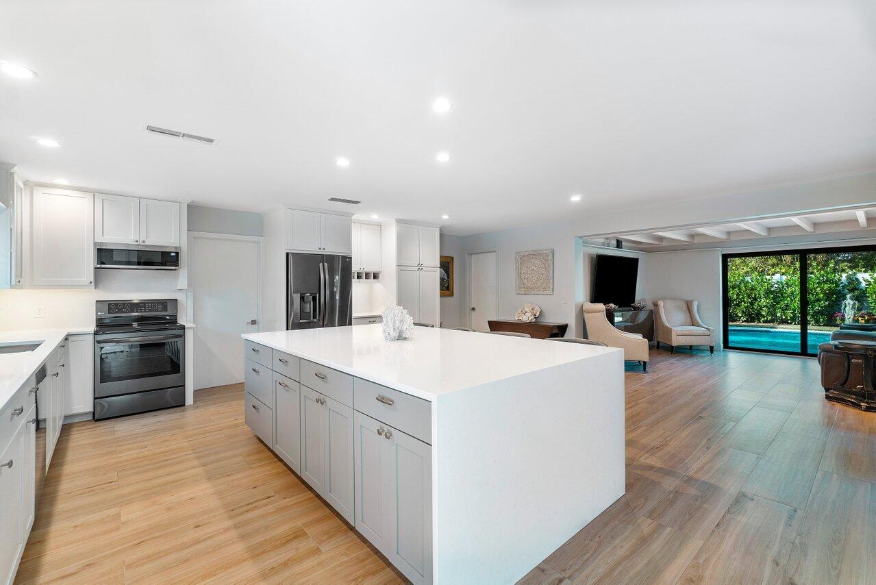 1280 Singer Drive Singer Island, FL 33404 - Photo 9 of 39 a large kitchen with stainless steel appliances kitchen island granite countertop a large center island and a sink