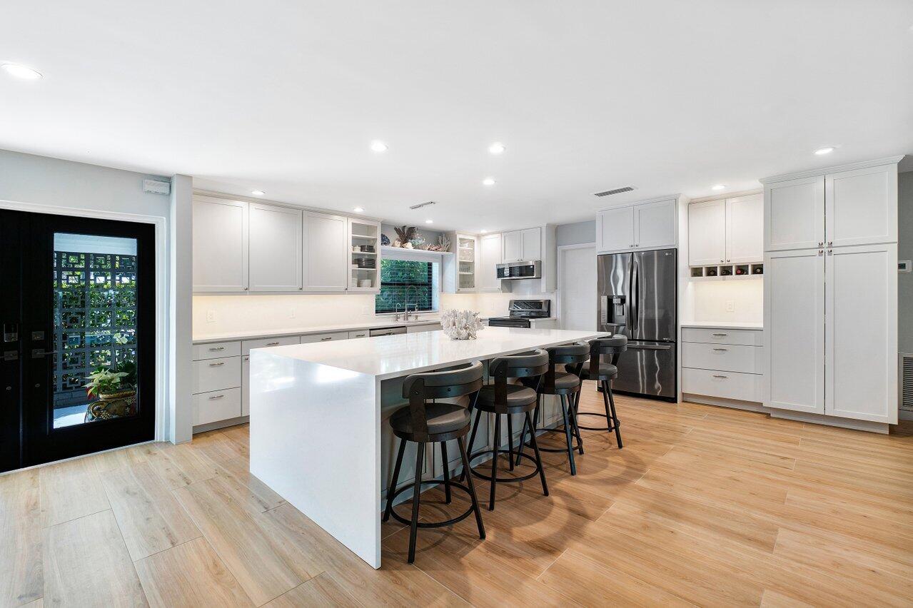 1280 Singer Drive Singer Island, FL 33404 - Photo 10 of 39 a kitchen with stainless steel appliances kitchen island granite countertop a table chairs sink and cabinets