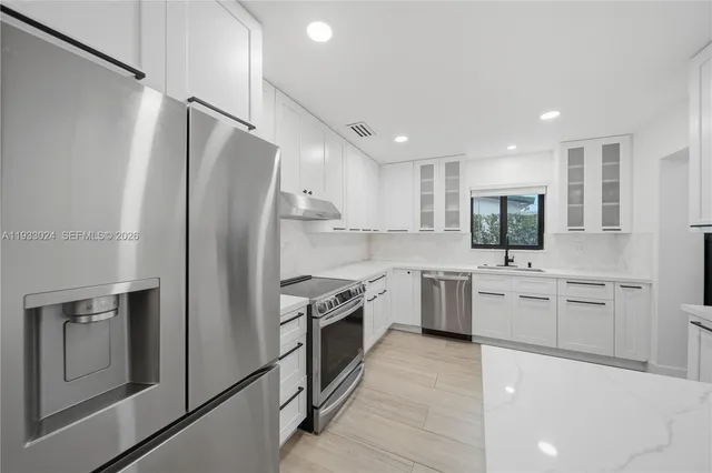 a kitchen with white cabinets and stainless steel appliances