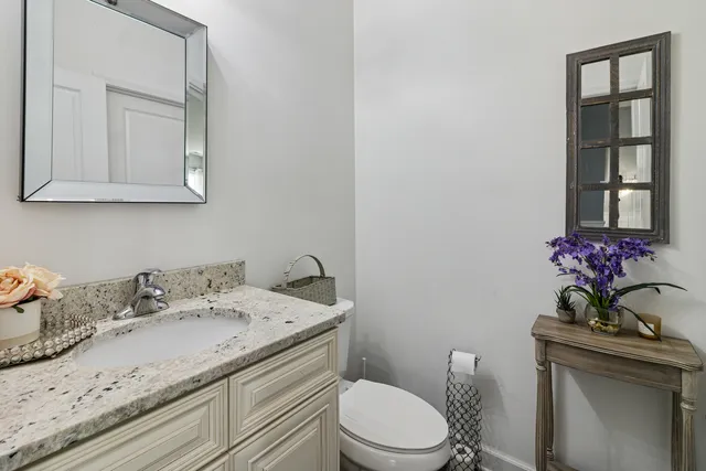 a bathroom with a granite countertop sink a toilet and mirror