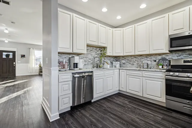 a kitchen with stainless steel appliances granite countertop a stove a sink and white cabinets