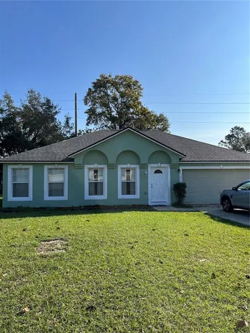 a front view of house with yard and trees in the background