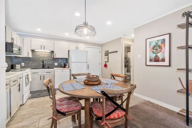 a view of a dining room with furniture a kitchen and chandelier